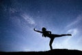 Milky Way with silhouette of a standing woman practicing yoga on the mountain. Beautiful landscape with meditating girl Royalty Free Stock Photo