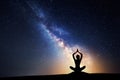 Milky Way and silhouette of a woman practicing yoga. Royalty Free Stock Photo