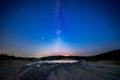 Milky way starry sky fading away into morning light with a muddy volcano in the foreground Royalty Free Stock Photo