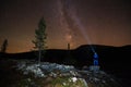 Milky way and starry sky over night scene outdoors in the forest and the mountains with boy and headlamp in the front. Royalty Free Stock Photo