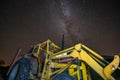 Milky way and starry sky over night scene outdoors, yellow old and rustic tractor used as foreground.