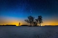 Milky way and starry sky over winter landscape and distant village Royalty Free Stock Photo