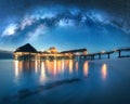 Milky Way and wooden bungalow on the water in summer starry night