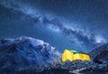 Milky Way, yellow glowing tent and mountains