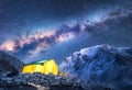 Milky Way, yellow glowing tent and mountains. Space