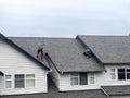 Mill Creek, WA USA - circa March 2023: Wide view of roofers working to repair roof materials in an apartment complex on an