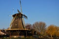 Mill traditionally made of wood along a river in the Netherlands. Old-fashioned way of collecting wind energy. Royalty Free Stock Photo