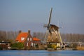 Mill traditionally made of wood along a river in the Netherlands. Old-fashioned way of collecting wind energy. Royalty Free Stock Photo