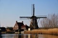 Mill traditionally made of wood along a river in the Netherlands. Old-fashioned way of collecting wind energy. Royalty Free Stock Photo