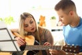 Millenial woman and guitar teacher play music