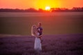 Millenial young mother holds little son in arms at sunset in purple lavender field. Lifestyle