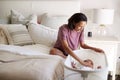 Millennial African American  mother sitting on her bed comforting her crying baby lying bedside her in his cot Royalty Free Stock Photo