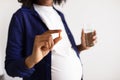 Millennial african american pregnant lady with big belly shows capsule pill, glass of water