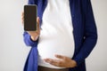 Millennial african american pregnant lady with big belly shows smartphone with blank screen