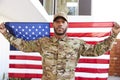Millennial African American  soldier standing outside modern building holding US flag, looking to camera, close up Royalty Free Stock Photo