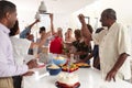 Millennial African American woman pouring champagne during a three generation family celebration at home