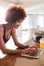 Millennial African American woman using laptop to check fitness data after her work out, vertical Royalty Free Stock Photo