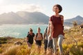 Millennial African American woman leading friends on an uphill hike by the coast, close up