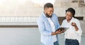 Millennial afro guy answering social survey to female interviewer outdoors Royalty Free Stock Photo