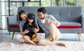 Millennial Asian happy family father drinking hot coffee while mother and dauthger sitting on cozy carpet floor smiling helping Royalty Free Stock Photo