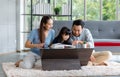 Millennial Asian happy family father and mother sitting on cozy carpet floor smiling helping teaching little young girl daughter Royalty Free Stock Photo