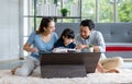 Millennial Asian happy family father and mother sitting on cozy carpet floor smiling helping teaching little young girl daughter Royalty Free Stock Photo