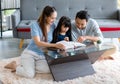 Millennial Asian happy family father and mother sitting on cozy carpet floor smiling helping teaching little young girl daughter Royalty Free Stock Photo