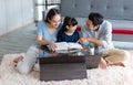 Millennial Asian happy family father and mother sitting on cozy carpet floor smiling helping teaching little young girl daughter Royalty Free Stock Photo