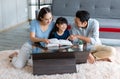 Millennial Asian happy family father and mother sitting on cozy carpet floor smiling helping teaching little young girl daughter Royalty Free Stock Photo