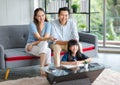 Millennial Asian happy family father and mother sitting on cozy sofa couch holding remote watching television while little young Royalty Free Stock Photo