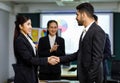 Millennial Asian Indian professional bearded male businessman shaking hands done deal female businesswoman in formal business suit Royalty Free Stock Photo