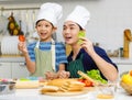 Millennial Asian little young boy chef wearing tall white cook hat and apron standing smiling holding sliced tomato posing Royalty Free Stock Photo