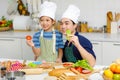 Millennial Asian little young boy chef wearing tall white cook hat and apron standing smiling holding sliced tomato posing Royalty Free Stock Photo