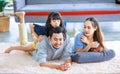 Millennial Asian lovely happy family father mother laying down on carpet floor while young daughter girl sitting piggy back on dad Royalty Free Stock Photo