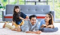 Millennial Asian lovely happy family father mother laying down on carpet floor while young daughter girl sitting piggy back on dad Royalty Free Stock Photo