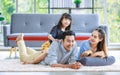 Millennial Asian lovely happy family father mother laying down on carpet floor while young daughter girl sitting piggy back on dad Royalty Free Stock Photo