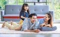 Millennial Asian lovely happy family father mother laying down on carpet floor while young daughter girl sitting piggy back on dad Royalty Free Stock Photo