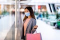 Millennial Asian woman in protective mask holding paper bags, window shopping, looking at new clothes at huge mall Royalty Free Stock Photo