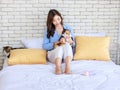 Millennial Asian young female owner sitting smiling leaning on pillow holding hugging cuddling tricolor short hair cat on lap with Royalty Free Stock Photo