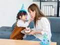 Millennial Asian young female teenager mother nanny babysitter sitting holding dish while little cute preschooler daughter Royalty Free Stock Photo