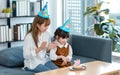 Millennial Asian young female teenager mother nanny babysitter wearing tall hat sitting together with little cute preschooler Royalty Free Stock Photo