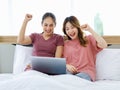 Asian young happy female LGBTQ lover couple sitting together on bed under warm blanket shopping Royalty Free Stock Photo