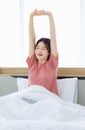 Millennial Asian young happy cheerful lazy sleepy female teenager sitting laying smiling on pillow under thick warm blanket on