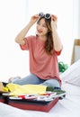 Millennial Asian young happy cheerful thoughtful female teenager sitting smiling on cozy bed in bedroom at home checking clothes Royalty Free Stock Photo