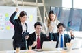 Millennial Asian young professional successful businessman in formal suit laughing holding fists up celebrating with female and Royalty Free Stock Photo