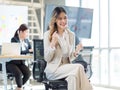 Millennial Asian young professional successful female businesswoman in formal suit high heels sitting smiling posing on chair Royalty Free Stock Photo