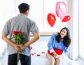 Millennial Asian young romantic lover couple unrecognizable male boyfriend holding red roses bouquet surprising female girlfriend