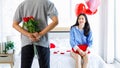 Millennial Asian young romantic lover couple unrecognizable male boyfriend holding red roses bouquet surprising female girlfriend