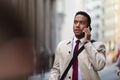 Millennial black businessman walking in a busy London street using smartphone, close up Royalty Free Stock Photo