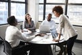 Millennial black businesswoman stands listening to corporate colleagues at a meeting, close up